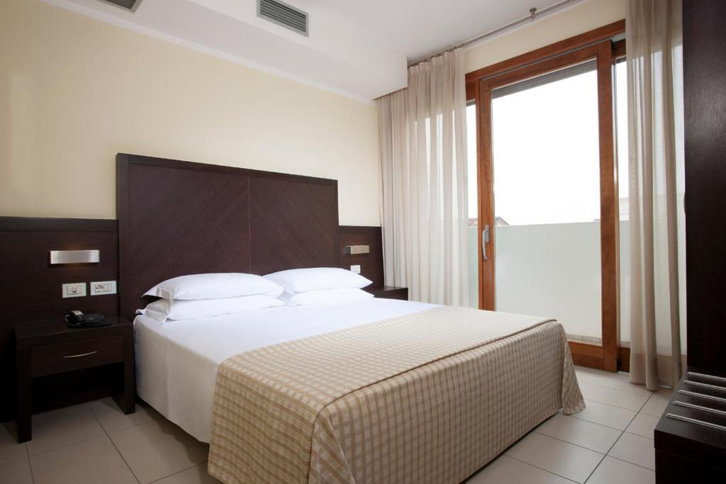 a bedroom with a large bed and a large window at Il Teatro in Lido di Jesolo