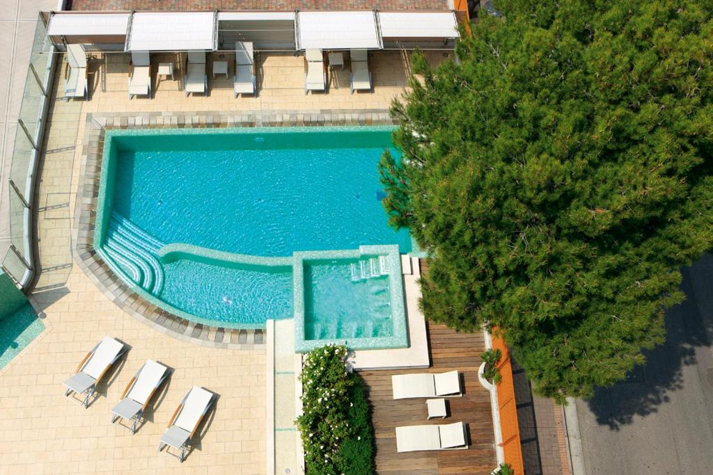 an overhead view of a swimming pool with chairs and trees at Il Teatro in Lido di Jesolo