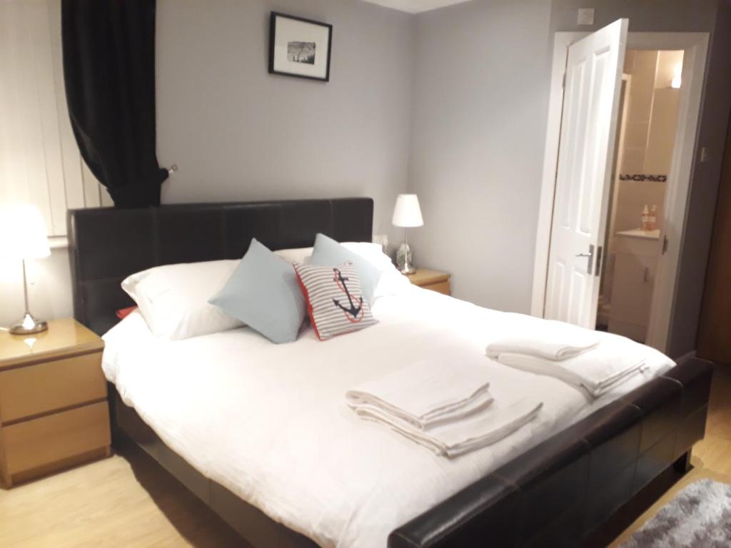 a bedroom with a large bed with white sheets and pillows at Coast 77 B&B in Poole