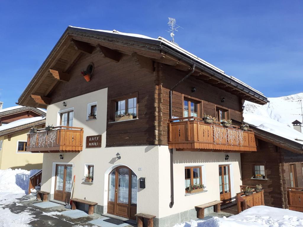 um grande edifício com varandas de madeira na neve em Baita Mauri em Livigno