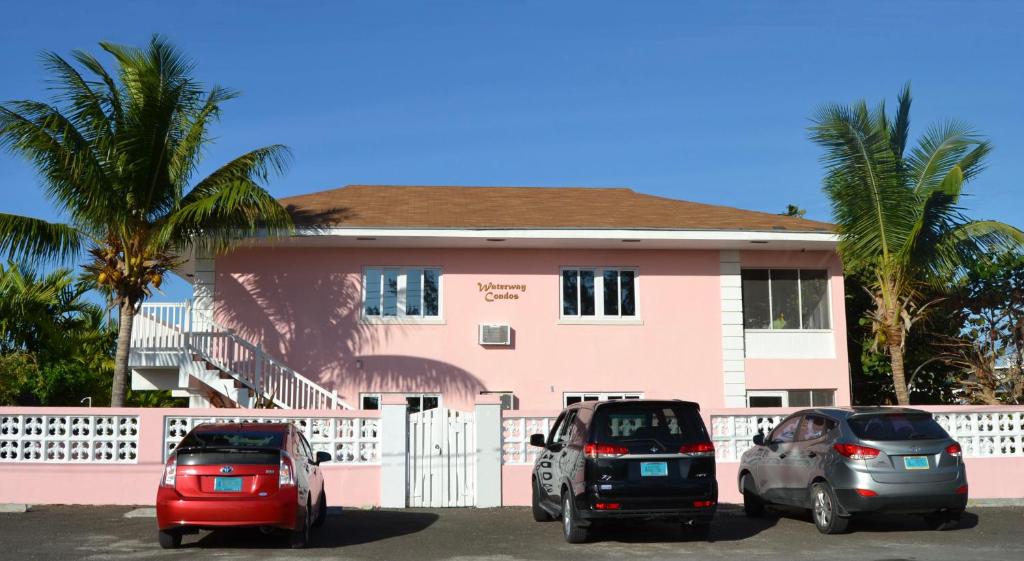 dos autos estacionados frente a un edificio rosa en Waterway Condos en Nassau