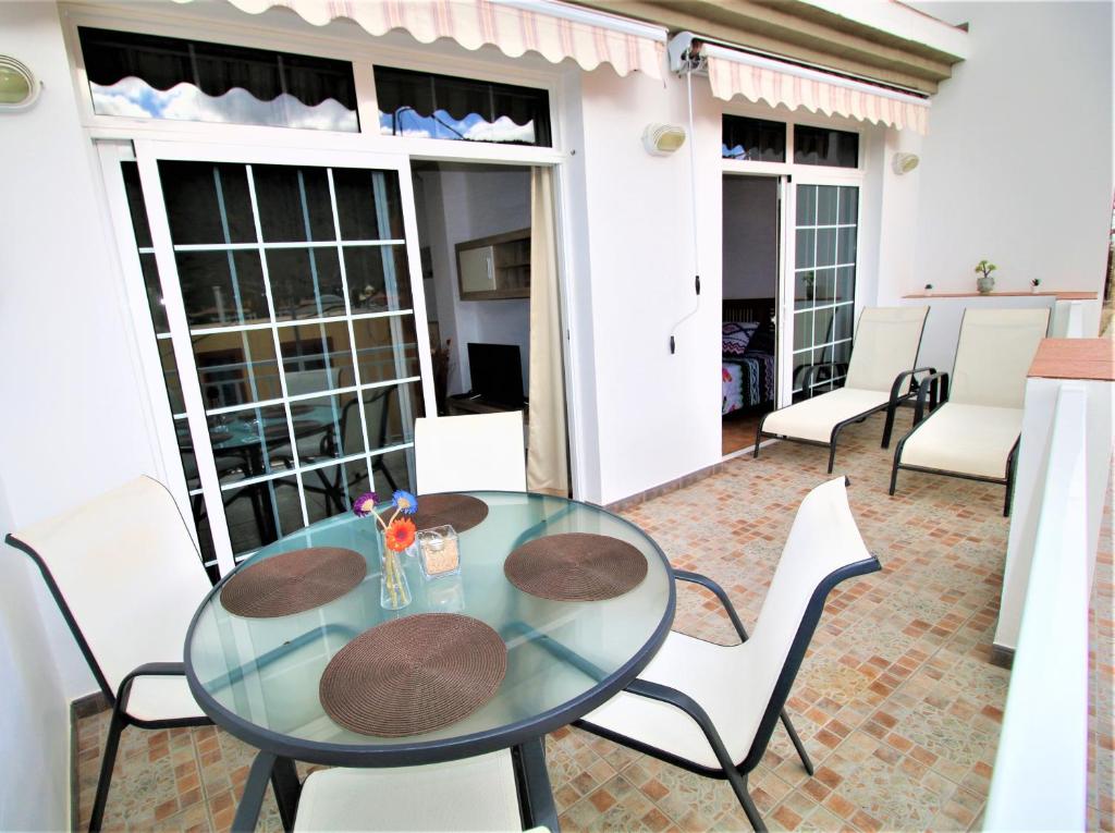 d'une terrasse avec une table et des chaises en verre. dans l'établissement Las Cascadas Mogan, à Puerto de Mogán