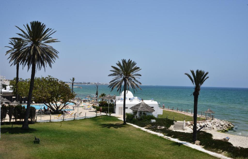 a view of a beach with palm trees and the ocean at Palmyra Club Nabeul in Nabeul