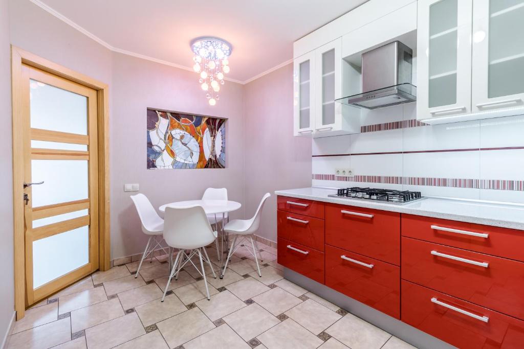 een keuken met rode kasten en een tafel met witte stoelen bij VIP 2 floors apartmens on MAIN SQUARE in Lviv