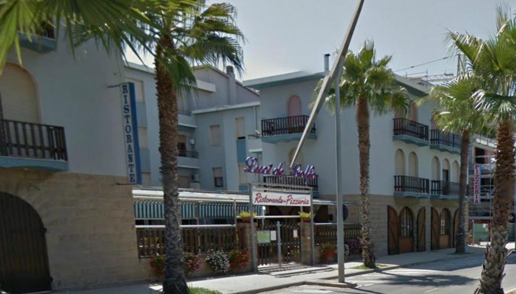 a street with palm trees in front of a building at Luci del Golfo in Alghero