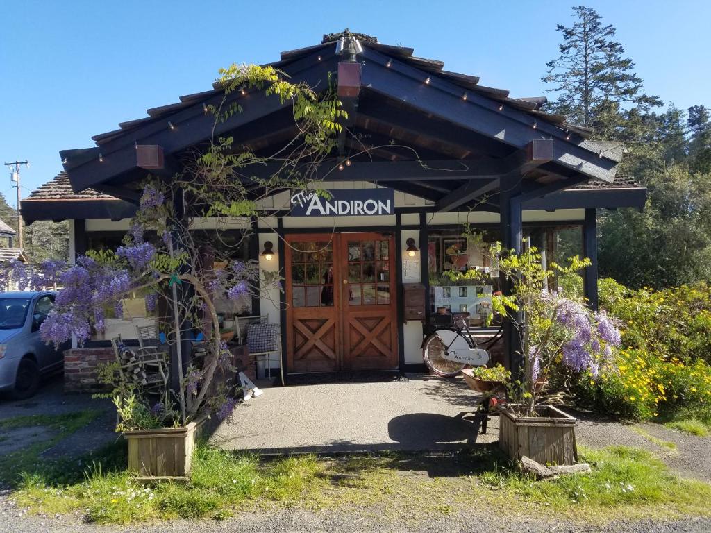 a shop with a wooden door and purple flowers at The Andiron Seaside Inn & Cabins in Little River