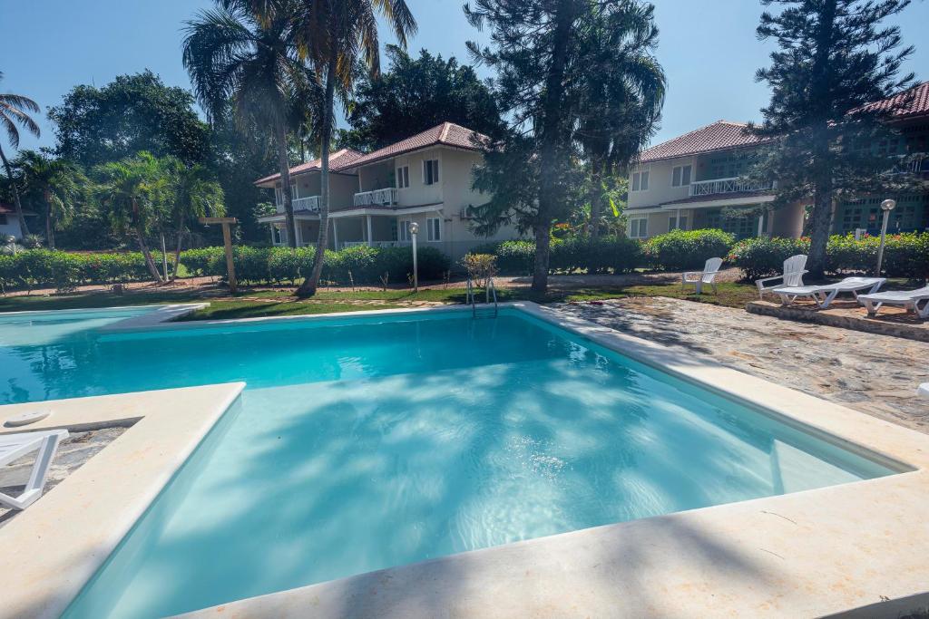 a swimming pool in front of a house at El Pelicano Apart-Hotel in Las Galeras