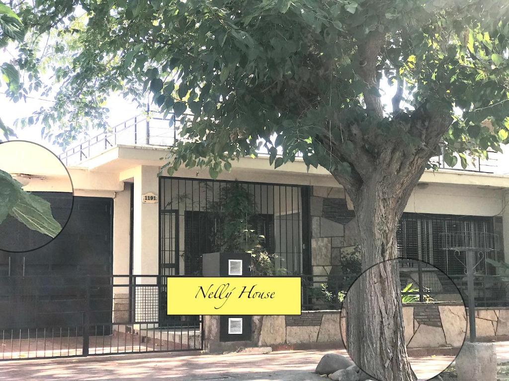 a building with a yellow sign in front of a tree at Nely's House en Mendoza in Guaymallen