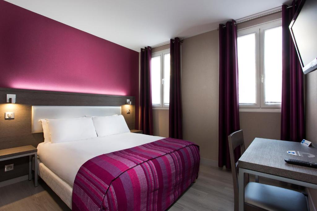 um quarto de hotel com uma cama com uma parede roxa em Hôtel des Pavillons em Paris