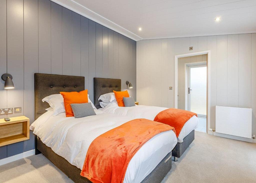 a large bedroom with two beds with orange pillows at Elton Furze Retreats 