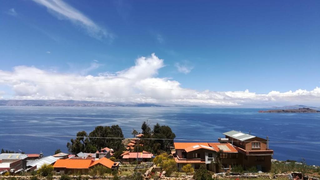 a house on a hill next to a body of water at Hostal Inti Wayra in Comunidad Yumani