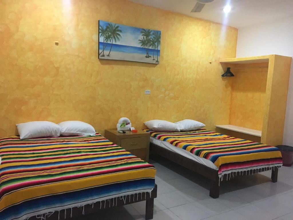 two beds in a room with yellow walls at Posada Olmeca in Playa del Carmen