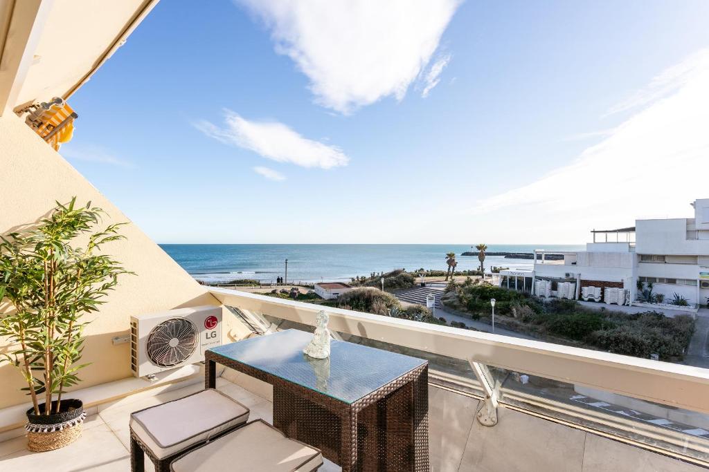 einen Balkon mit einem Tisch und Stühlen sowie Meerblick in der Unterkunft Bali Heliopolis naturiste in Cap d'Agde