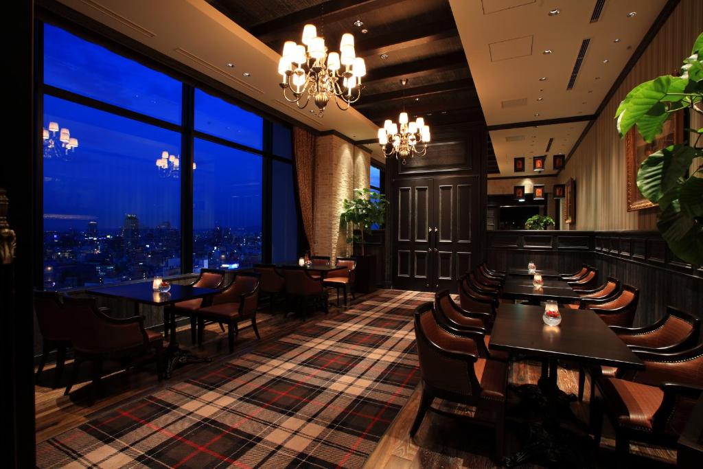 a restaurant with tables and chairs and a view of the city at Hotel Monterey Grasmere Osaka in Osaka