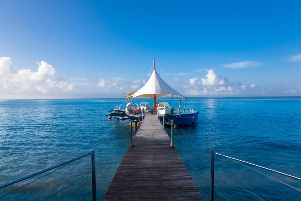 eine Anlegestelle mit einem Boot auf dem Wasser in der Unterkunft Coco de Mer Hotel and Black Parrot Suites in Grand'Anse Praslin