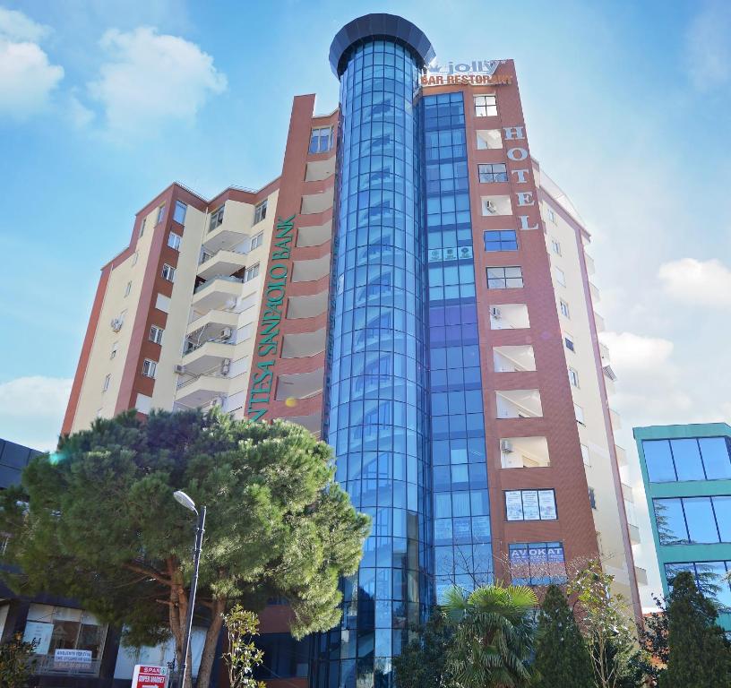 a tall building with a tree in front of it at Jolly Hotel in Lezhë