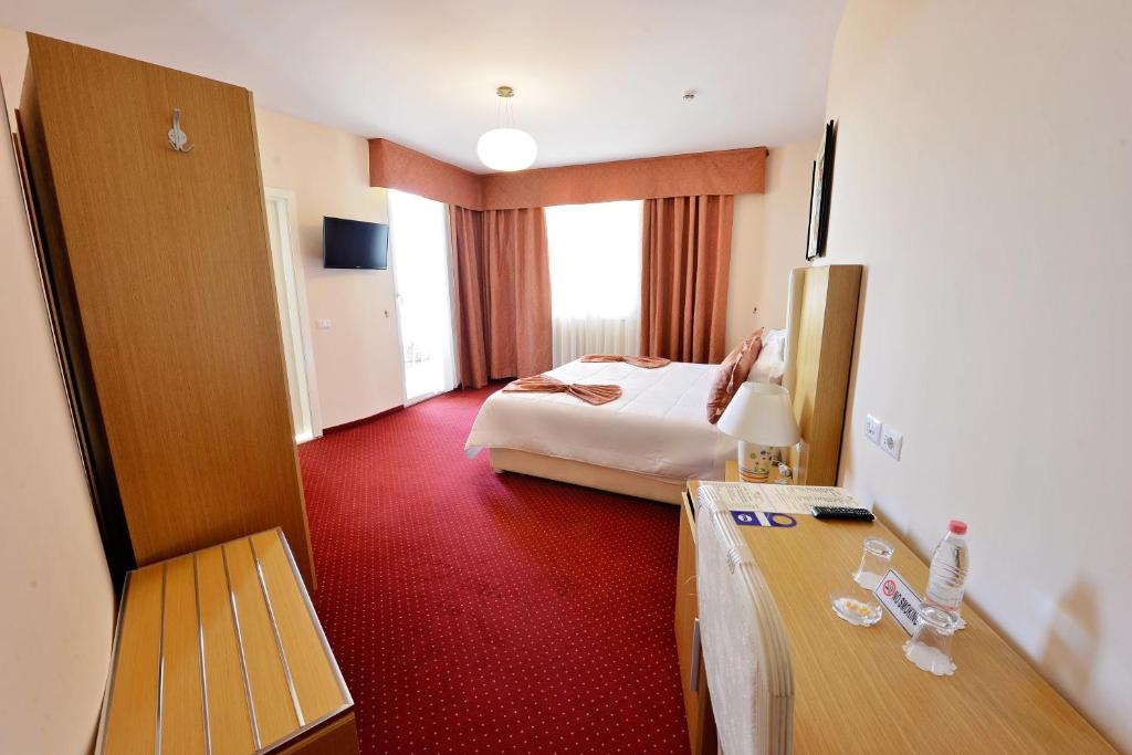 a hotel room with a bedroom with a bed and a desk at Jolly Hotel in Lezhë