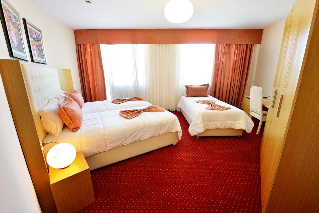 a hotel room with two beds and a window at Jolly Hotel in Lezhë