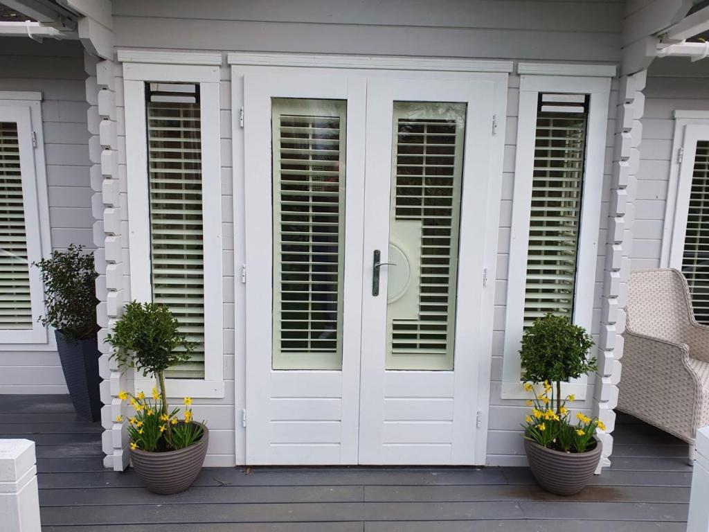 a white door on a house with potted plants at Willow House B&B in West Wittering