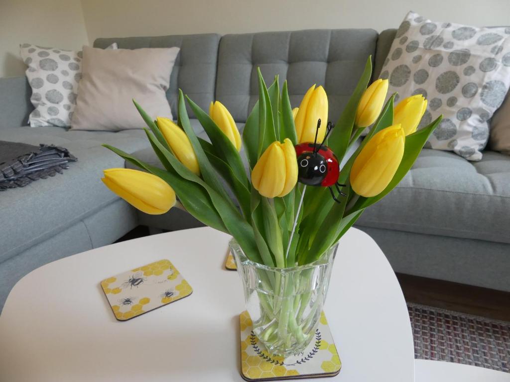 un vase rempli de fleurs jaunes sur une table dans l'établissement Ferienwohnung Sünteltraum, à Hameln