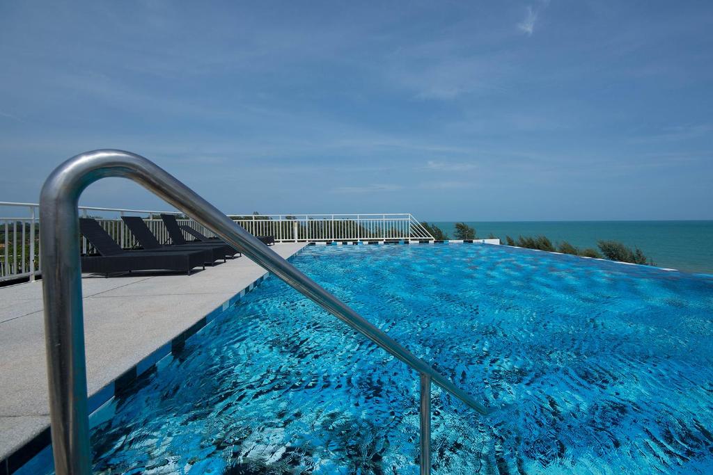 una piscina con corrimano di metallo accanto all'oceano di GrandBeach Duplex Sea view by malai a Ban Tha Fat
