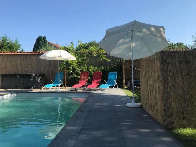 - un groupe de chaises et un parasol à côté de la piscine dans l'établissement L'Atelier Zen, à Sarreguemines