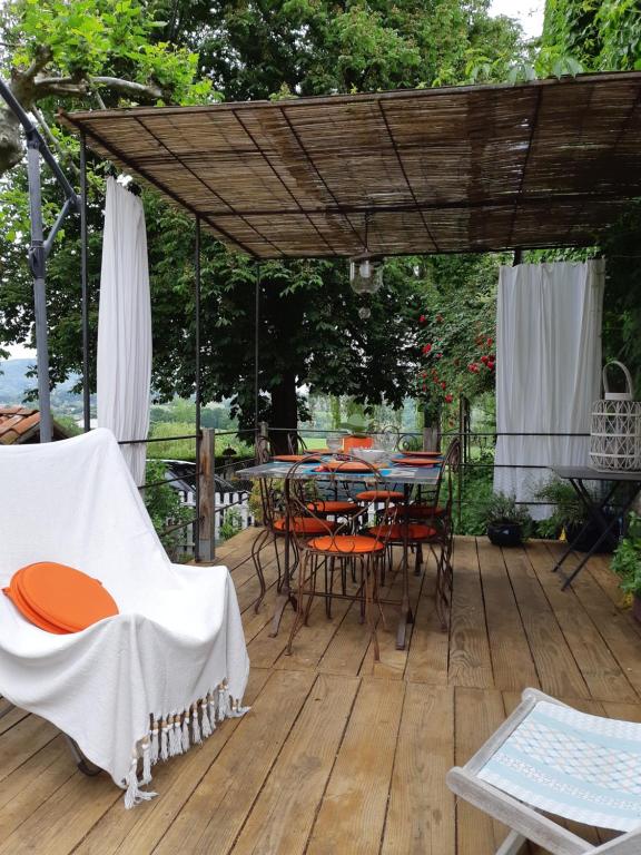 eine Terrasse mit Tischen und Stühlen sowie einer Holzterrasse in der Unterkunft la maison d'Anna chambres d hôtes in Ganac