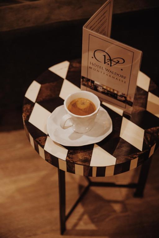 a cup of coffee on a table with a box at Waldorf Montparnasse in Paris