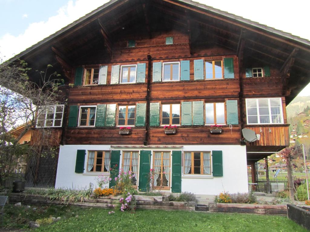 een houten huis met groen en wit bij Chalet Halten in Lenk