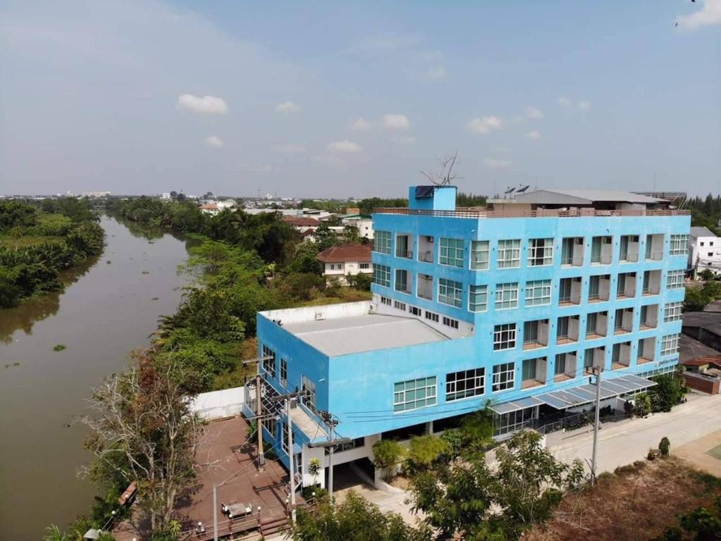 a large blue building next to a river at Like Residence in Suratthani