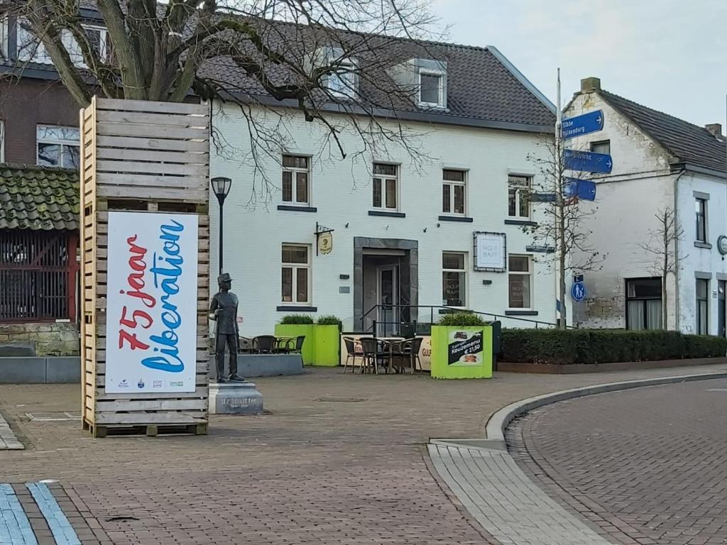 een wit gebouw met een bord ervoor bij B&B Liberation Margraten in Margraten