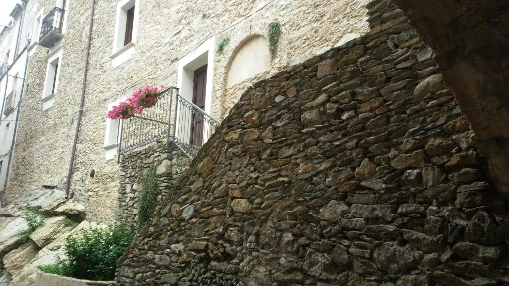 eine Steinmauer mit einem Fenster und Blumen auf dem Balkon in der Unterkunft Hotel Palazzo Bruni in Maierà