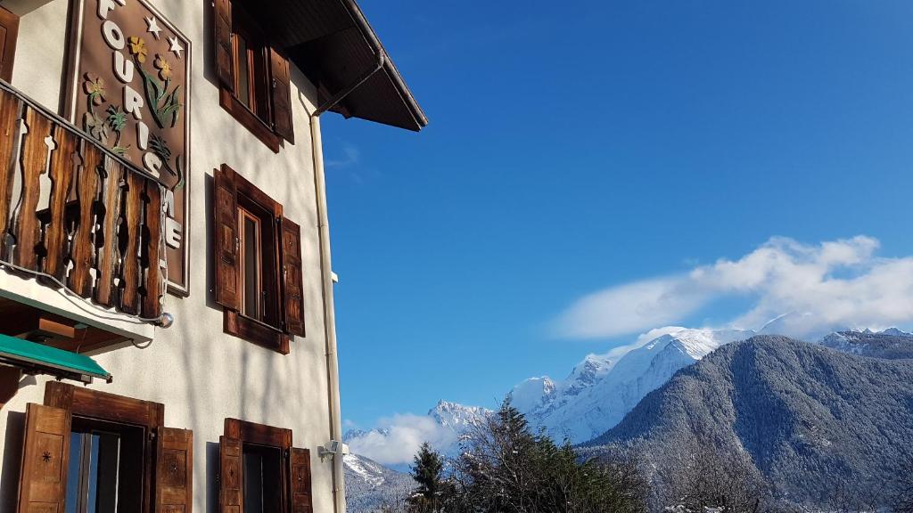 a building with windows and mountains in the background at HOTEL Le TOURISME in Passy