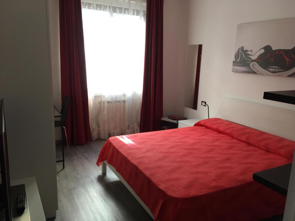 um quarto com uma cama vermelha e uma grande janela em Matt5, il tuo angolino triestino em Trieste