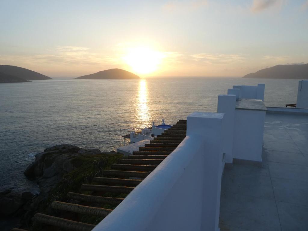 una puesta de sol sobre el océano con escaleras que conducen al agua en Casa Arraial do Cabo Beachfront en Arraial do Cabo
