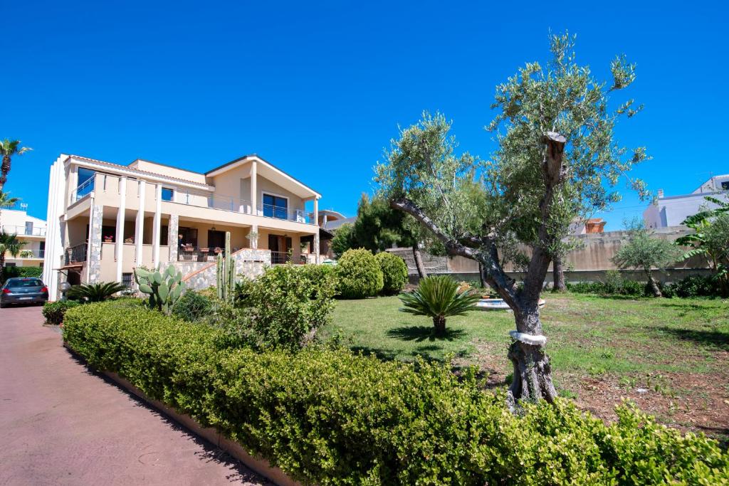 a house with a tree in the front yard at Villa Dell'Artista Fronte Spiaggia - SiciliaVacanza in Avola
