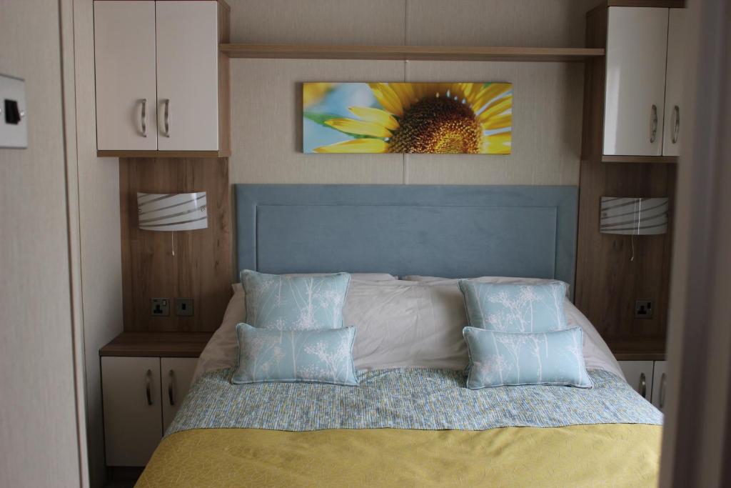 1 dormitorio con 1 cama con una pintura de girasol en Life Begins @ 40 Sun Valley Park, en St Austell