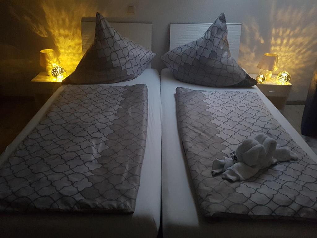 2 camas con almohadas y un osito de peluche. en Ferienwohnung Schinderhannes, en Miehlen