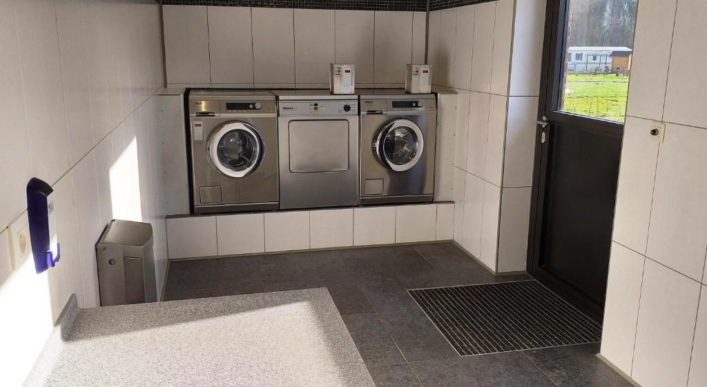 a laundry room with two washing machines and a window at Vakantiepark Wilhelm Tell Superieur Chalet in Opglabbeek