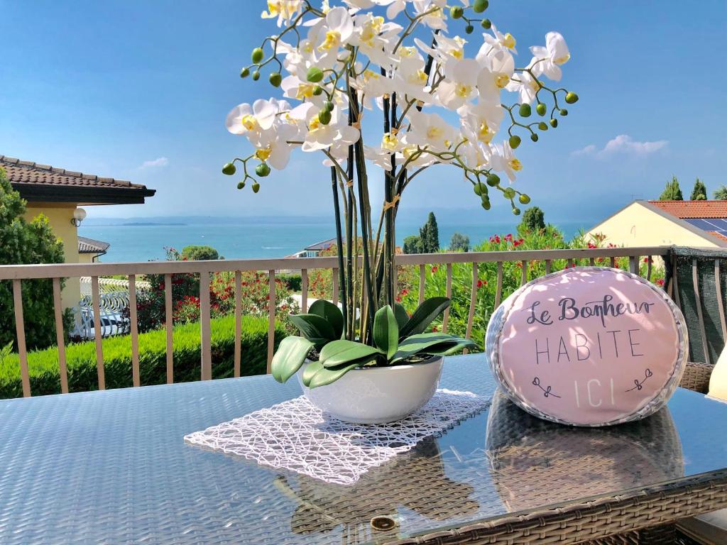 einen Tisch mit einer Vase mit einer Blume darauf in der Unterkunft GardaLake View Villa in Lazise