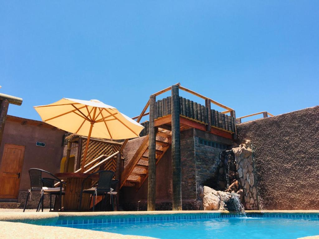 uma piscina com um deque e um guarda-sol ao lado de um edifício em La Casa de José em San Pedro de Atacama