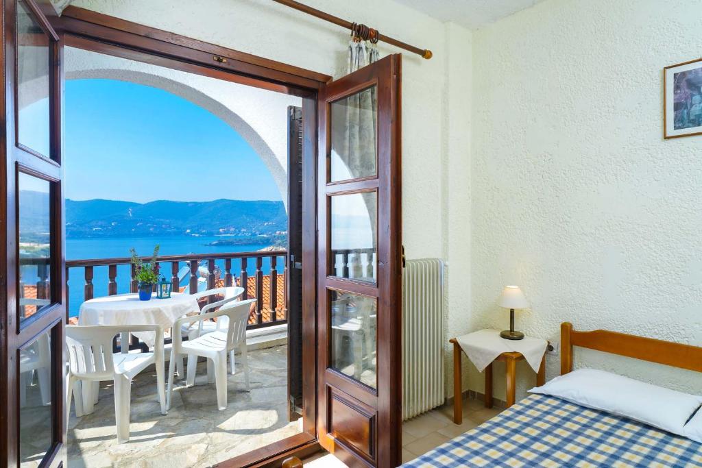 - une chambre avec un balcon doté d'un lit et d'une table dans l'établissement Kritikos Apartments, à Pyrgadikia