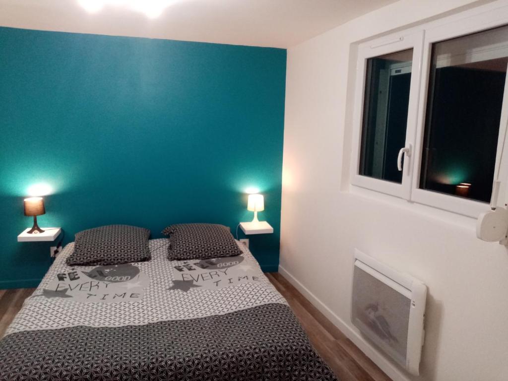 een slaapkamer met een bed en een blauwe muur bij Bienvenue chez vous in Honfleur
