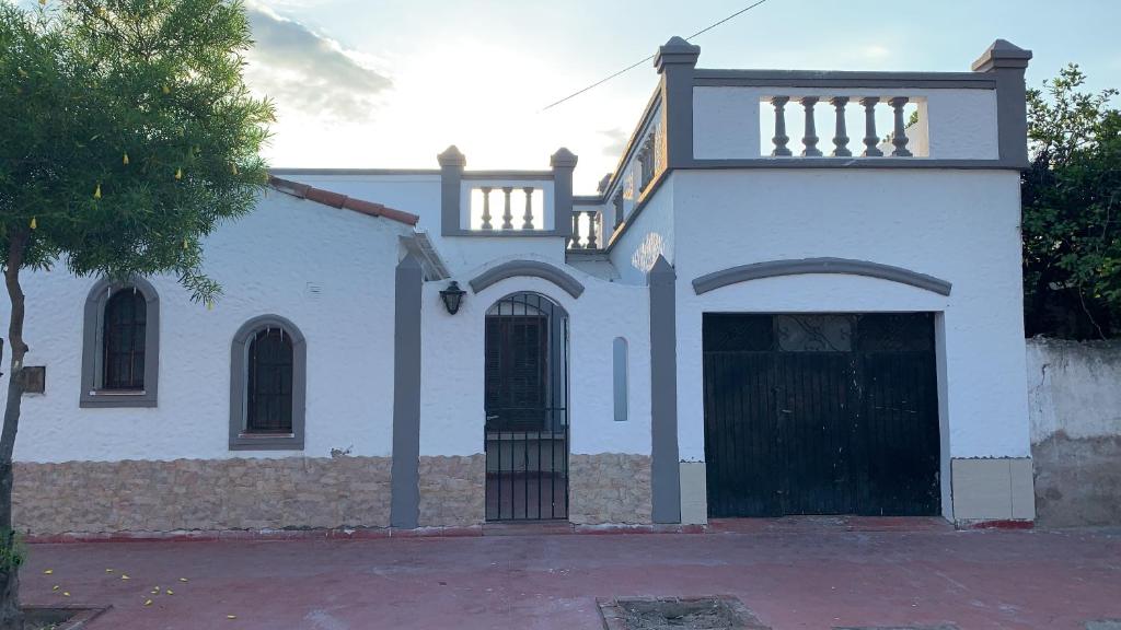 una casa blanca con una puerta negra y un edificio en Las Rosas - bulnes 121 en La Rioja
