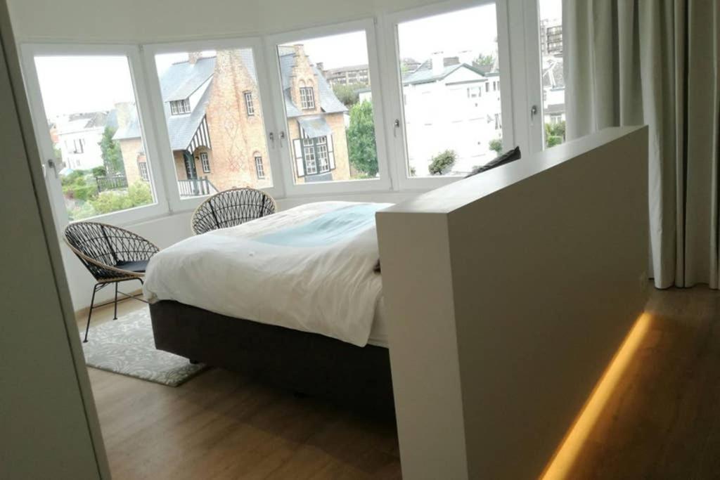 a bedroom with a bed and a large window at Villa My Corner in De Panne
