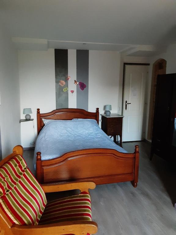 1 dormitorio con cama de madera y sofá en Chambre D'Hôtes avec petit Déjeuner, en Remilly-les-Pothées