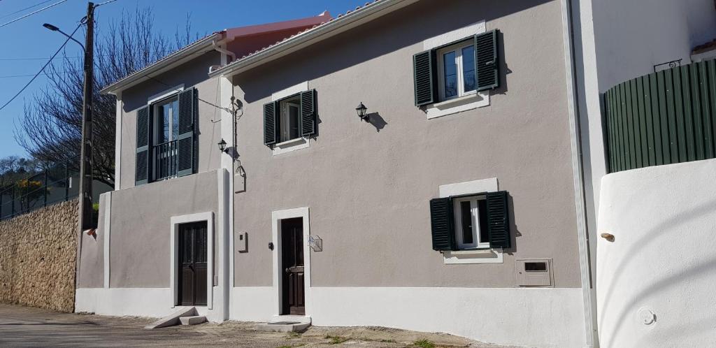 un edificio con persianas blancas y negras. en AL - HaoleGuestHouse, en Sobral de Monte Agraço