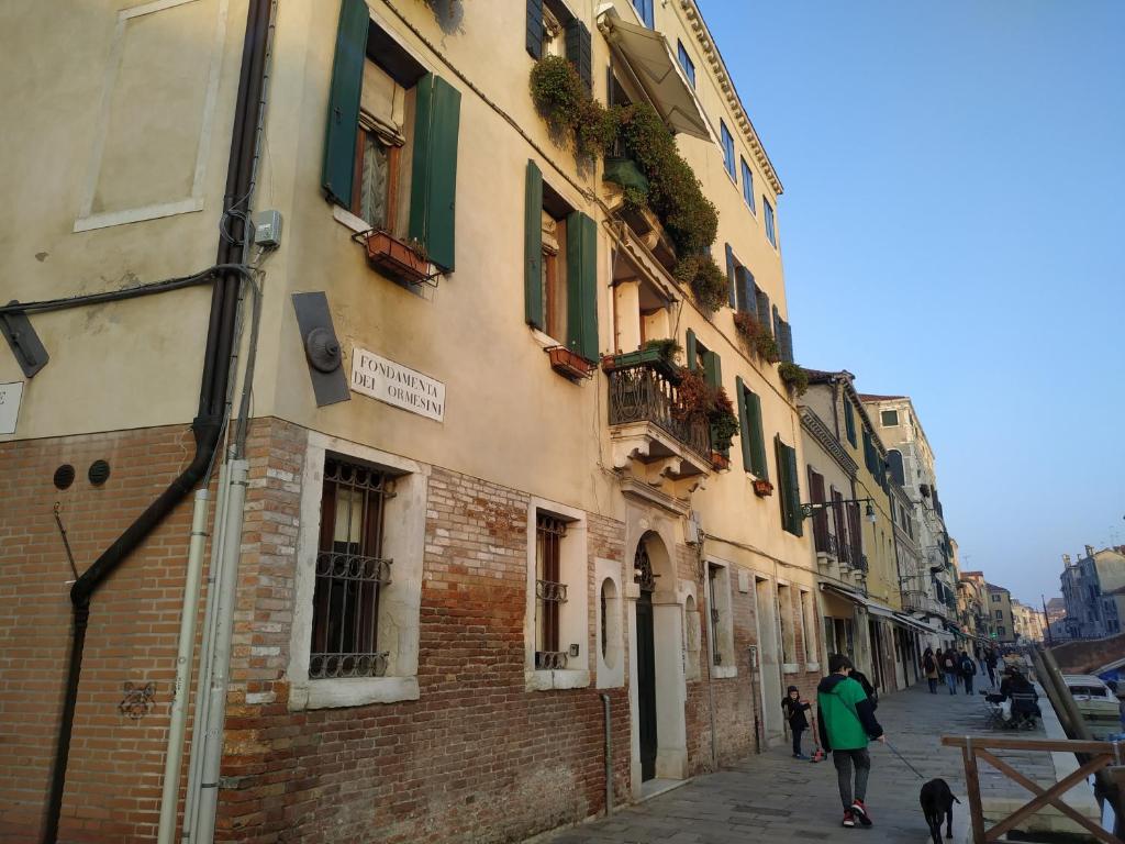 Ein Mann, der mit einem Hund auf einer Straße neben einem Gebäude läuft. in der Unterkunft Guizzo apartment Venezia in Venedig