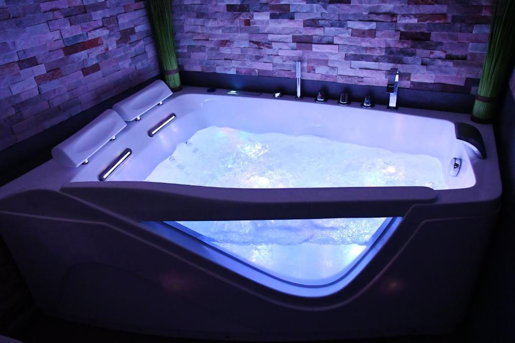 a large bath tub with a window in a room at Appartement Tropical et JACUZZI Balnéothérapie Draveil in Draveil