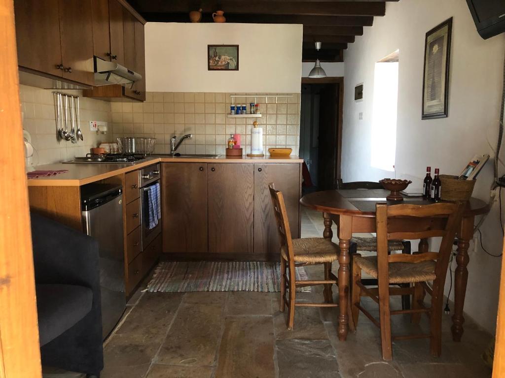 uma cozinha com uma mesa de madeira, uma mesa e cadeiras em ANOI 1-bedroom country House em Episkopi Pafou